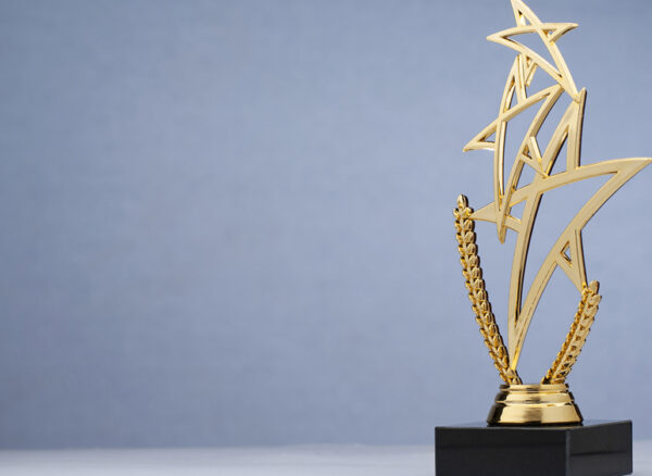 Shiny golden statue award in shape of triple star with black pedestal